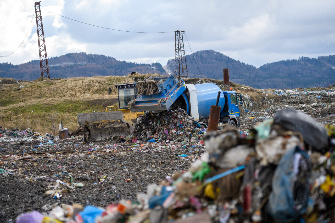 Garbage truck unloading waste on landfill, environmental concept. Copy space.