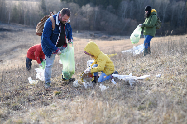 Young girl among eco activists picking up litter in nature, environmental pollution, eco activism and plogging concept.