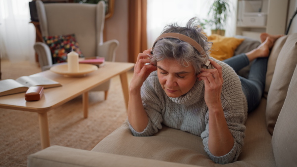 Mature woman listening to music on her headphones, using phone, enjoying.