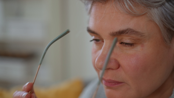 Close up of attractive mature woman putting on optical glasses.