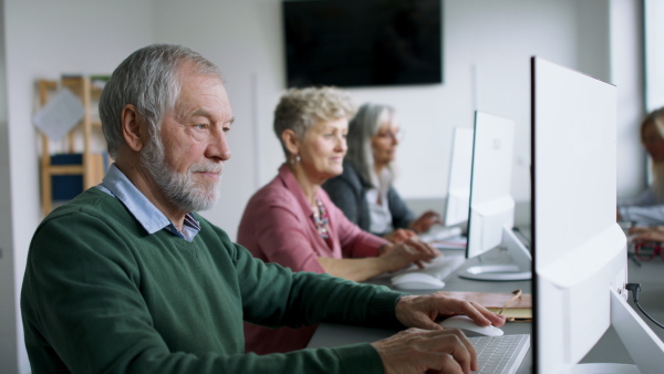 Group of cheerful senior people attending computer and technology education class.