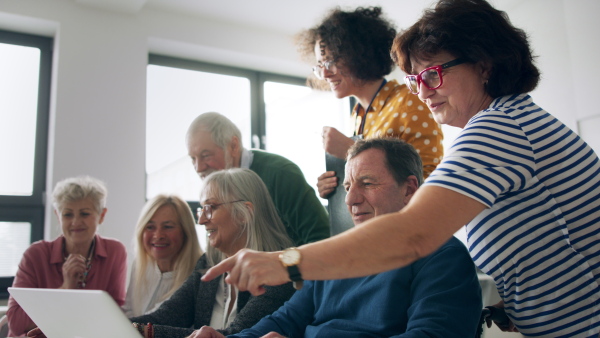 Group of cheerful senior people attending computer and technology education class.