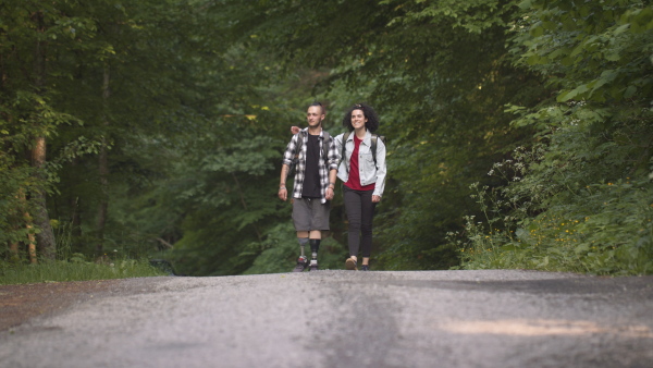 Disabled young man wearing leg prosthetis enjoying a walk outdoors with his assitant friend.