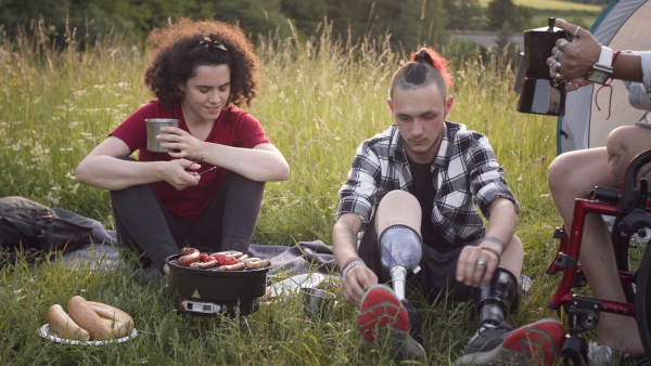 Disabled teenager with leg prosthetis enjoying barbeque with woman friend outdoors.