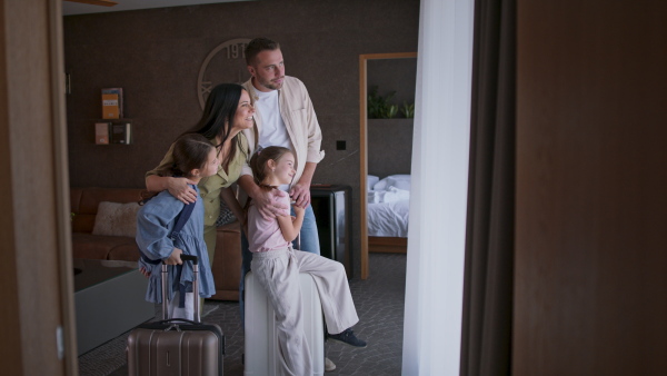 A happy young family with two children enetring room at luxury hotel, summer holiday.