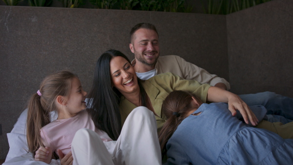 A happy young family with two children lying on bed at hotel, summer holiday.