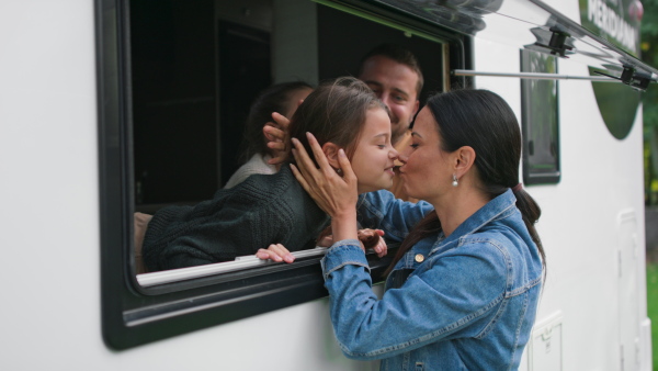 A happy young mother kissing ker kids to say goodbye before caravan trip with their father.