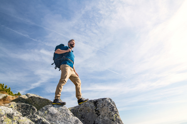 Mature man with backpack hiking in mountains in summer. Copy space.