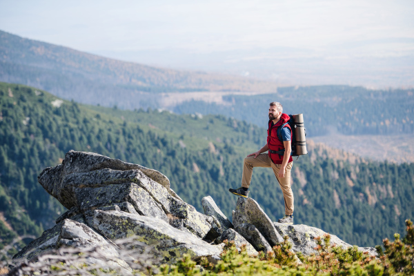 Mature man with backpack hiking in mountains in summer, resting.