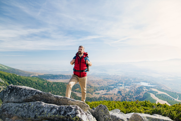 Mature man with backpack hiking in mountains in summer, resting.