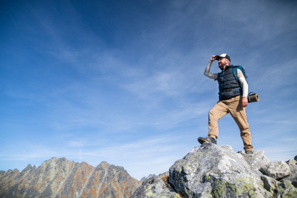 Mature man with backpack hiking in mountains in summer. Copy space.