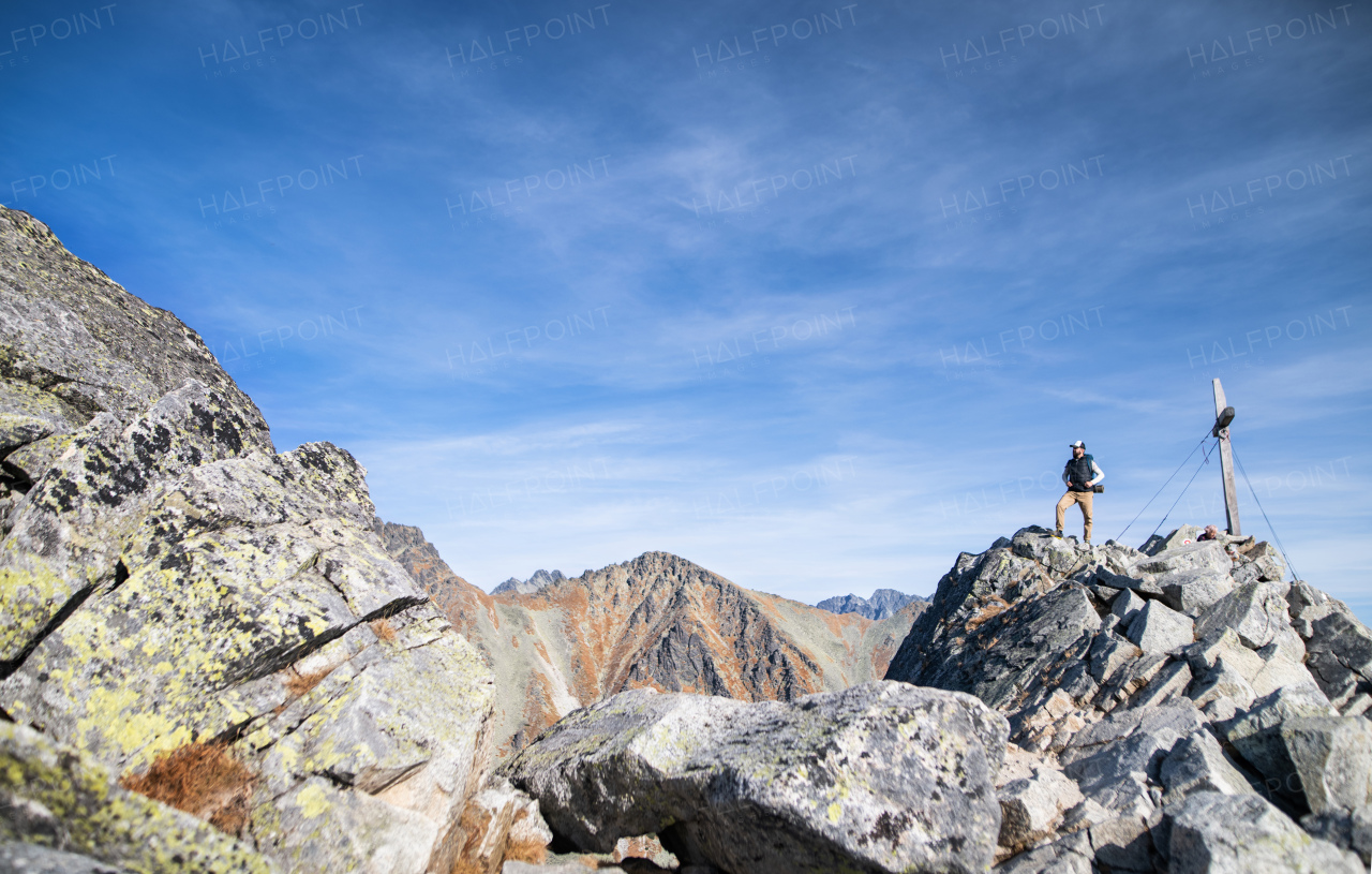 Mature man with backpack hiking in mountains in autumn, resting. Copy space.