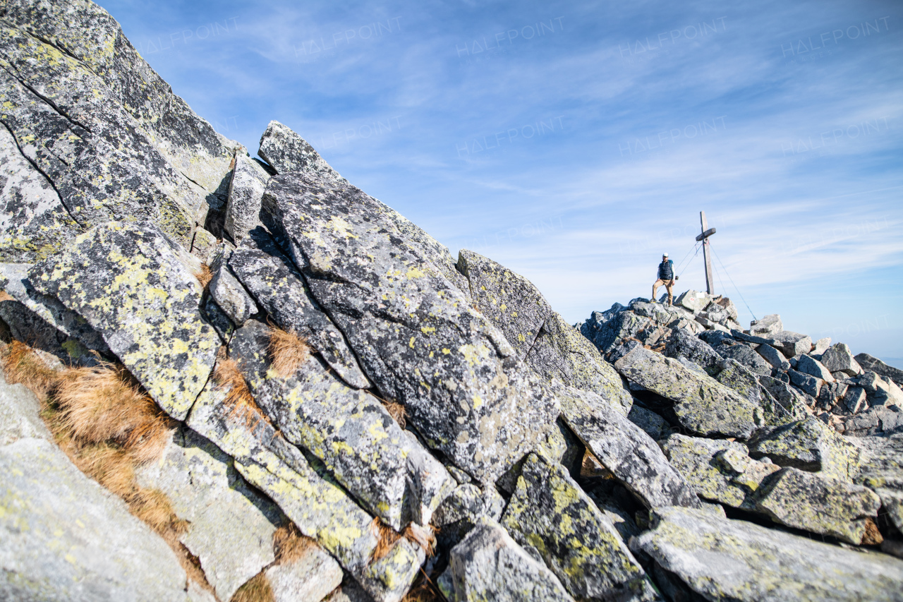 Mature man with backpack hiking in mountains in autumn, resting by the cross.