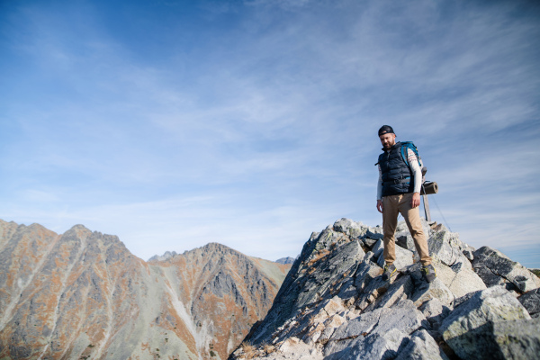 Mature man with backpack hiking in mountains in summer. Copy space.