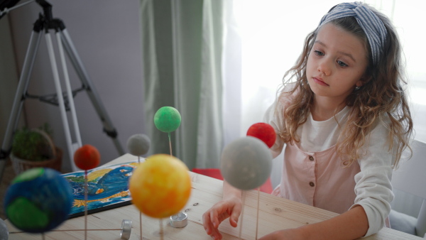 A little concentrated girl making a solar system model at home, homeschooling.