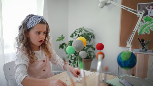 A little concentrated girl making a solar system model at home, homeschooling.