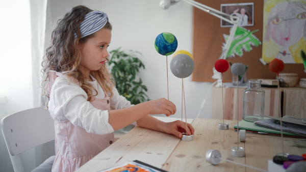 A little concentrated girl making a solar system model at home, homeschooling.