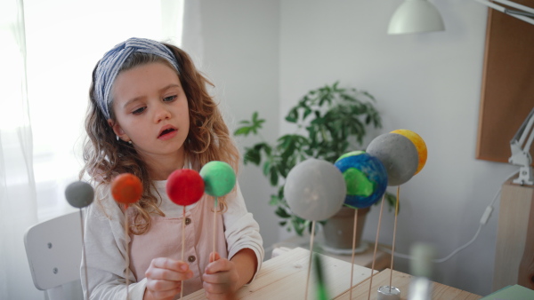 A little concentrated girl making a solar system model at home, homeschooling.