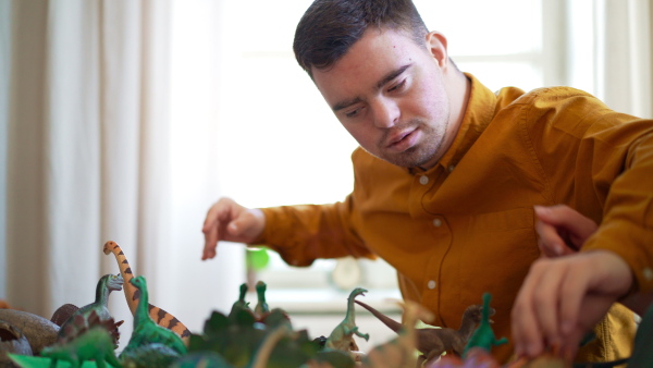 A close up of young man with Down syndrome with his tutor learning about dinosaurs, homeschooling.