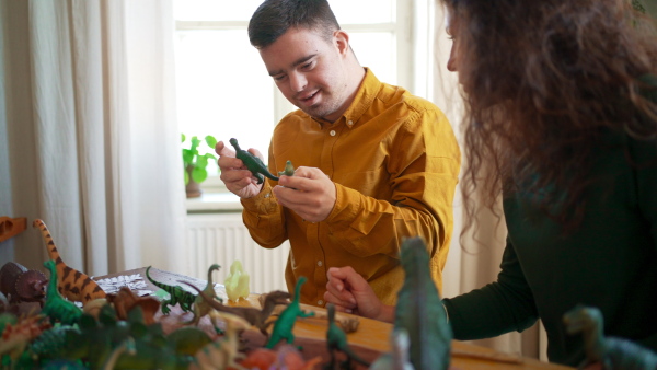 A young man with Down syndrome with his tutor learning about dinosaurs, homeschooling.