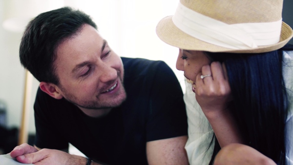 A close-up of young affectionate couple lying on bed indoors at home, talking.