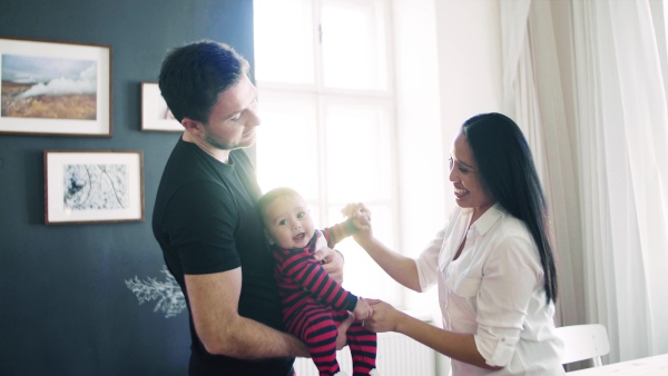 A young happy couple with a baby dancing indoors, having fun.