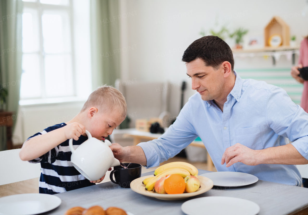 A happy family with down syndrome son at the table, having breakfast.