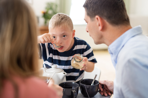 A happy family with down syndrome son at the table, having breakfast.