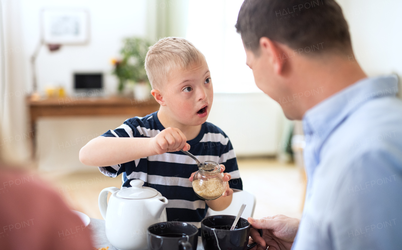 A happy family with down syndrome son at the table, having breakfast.