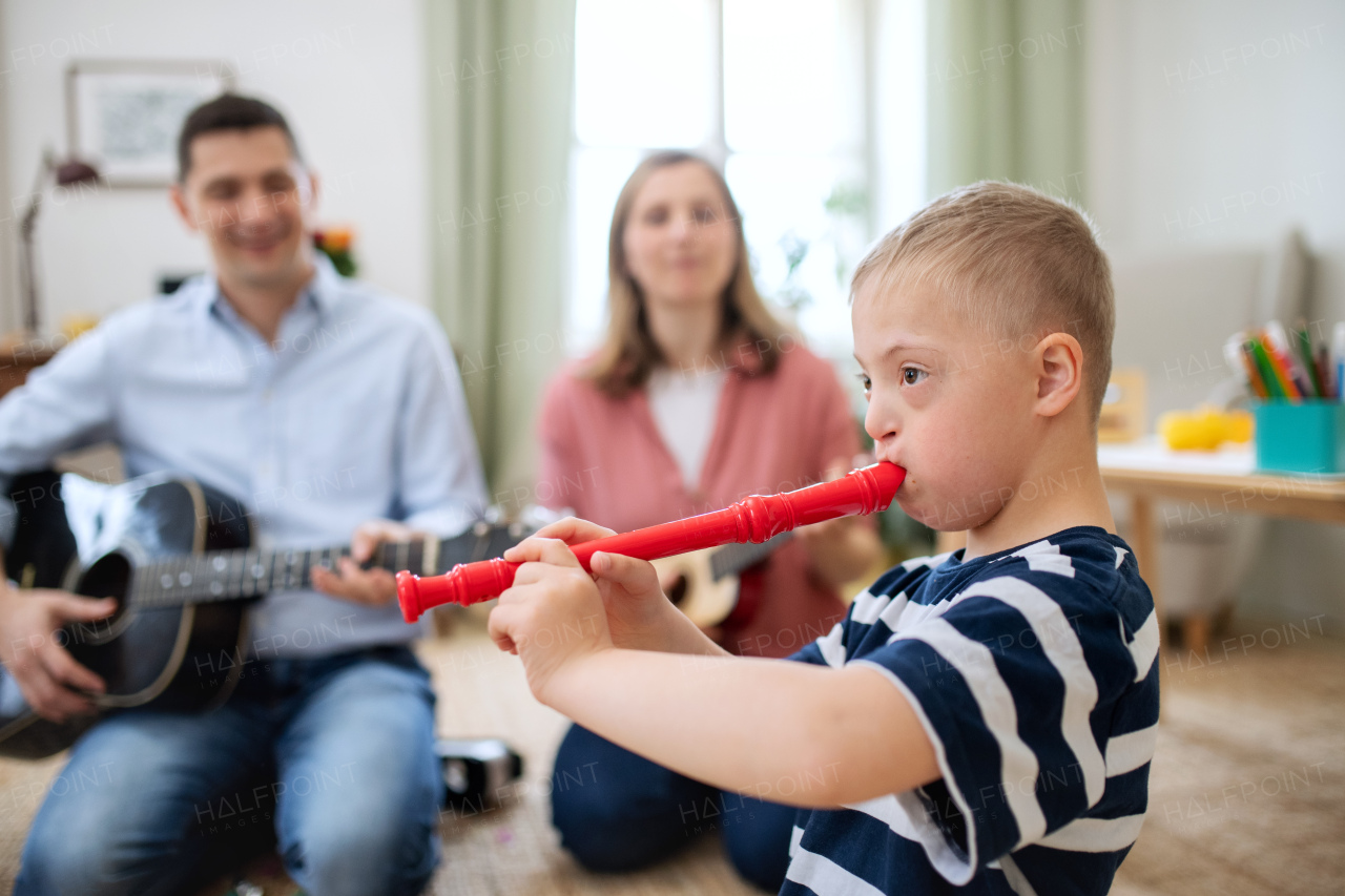 A cheerful down syndrome boy with parents playing musical instruments, laughing.