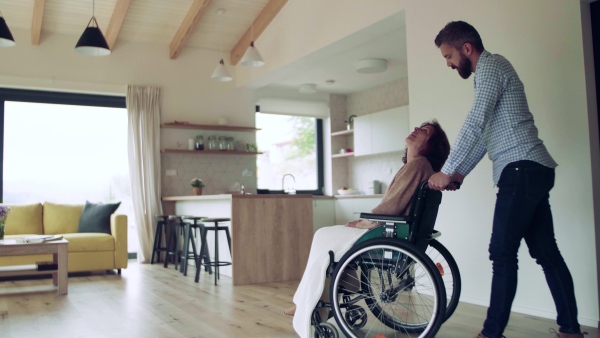 Health visitor and a disabled senior woman in wheelchair during home visit.