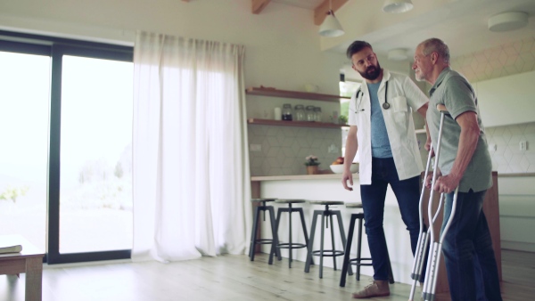 Health visitor and a senior man with crutches during home visit, talking when walking.