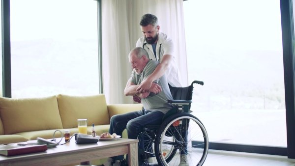 Health visitor helping a senior man with wheelchair during home visit.