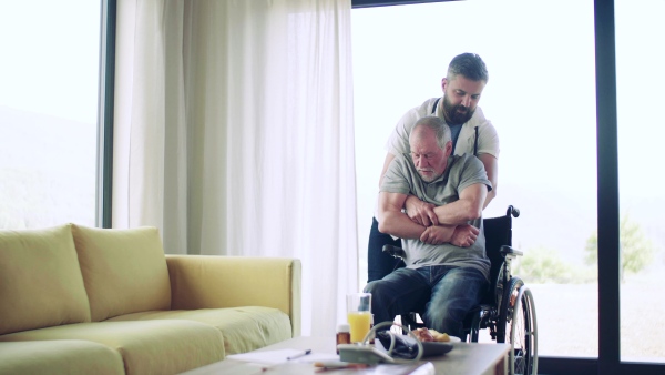 Health visitor helping a senior man with wheelchair during home visit.