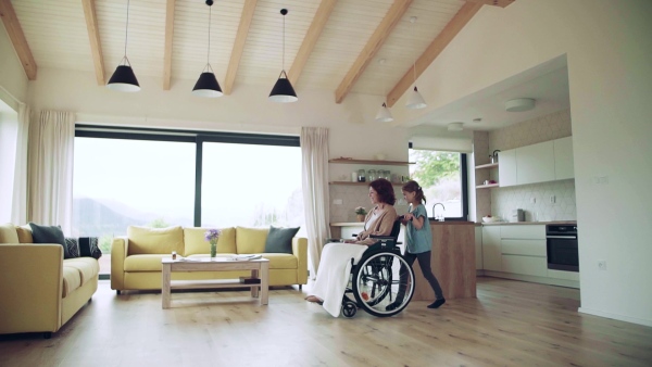 A small girl and her senior grandmother in wheelchair indoors at home. Slow motion.