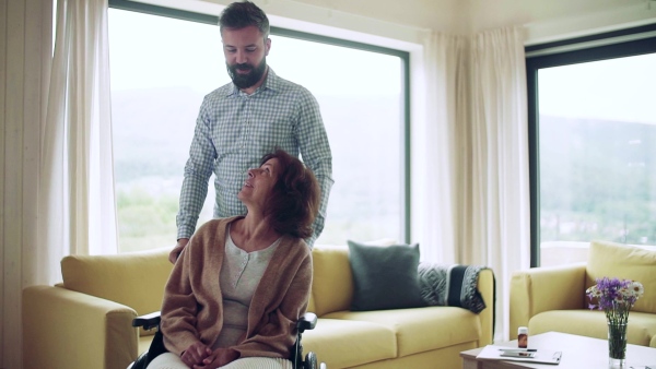 Health visitor and a disabled senior woman in wheelchair during home visit. Slow motion.