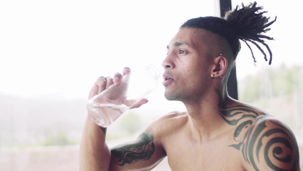 A mixed race young man resting after doing exercise indoors at home, a body workout.