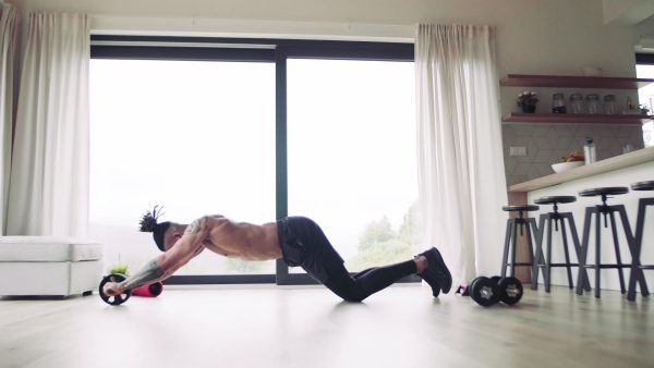 A mixed race young man with tattoo doing exercise indoors at home, a body workout.