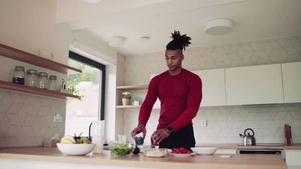 An active mixed race young sporty man indoors at home, preparing healthy food.