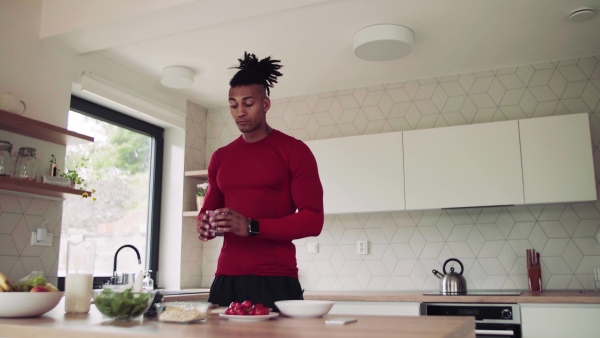 An active mixed race young sporty man indoors at home, preparing healthy food.