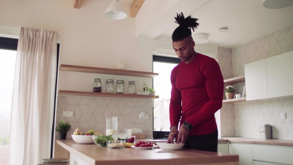 An active mixed race young sporty man indoors at home, preparing healthy food.