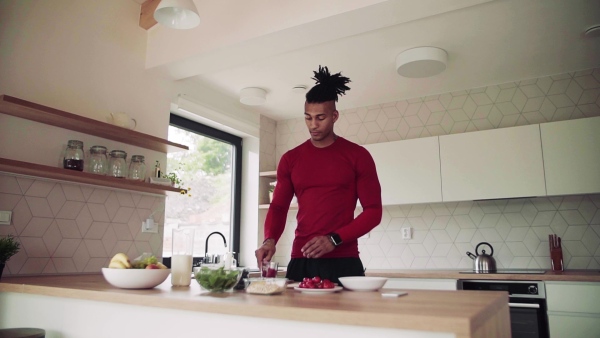 An active mixed race young sporty man indoors at home, preparing healthy food. Slow motion.