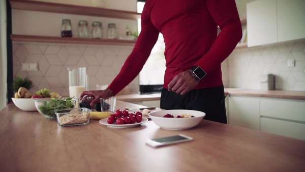 A midsection of young sporty man indoors at home, preparing healthy food. Slow motion.