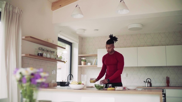 An active mixed race young sporty man indoors at home, preparing healthy food. Slow motion.