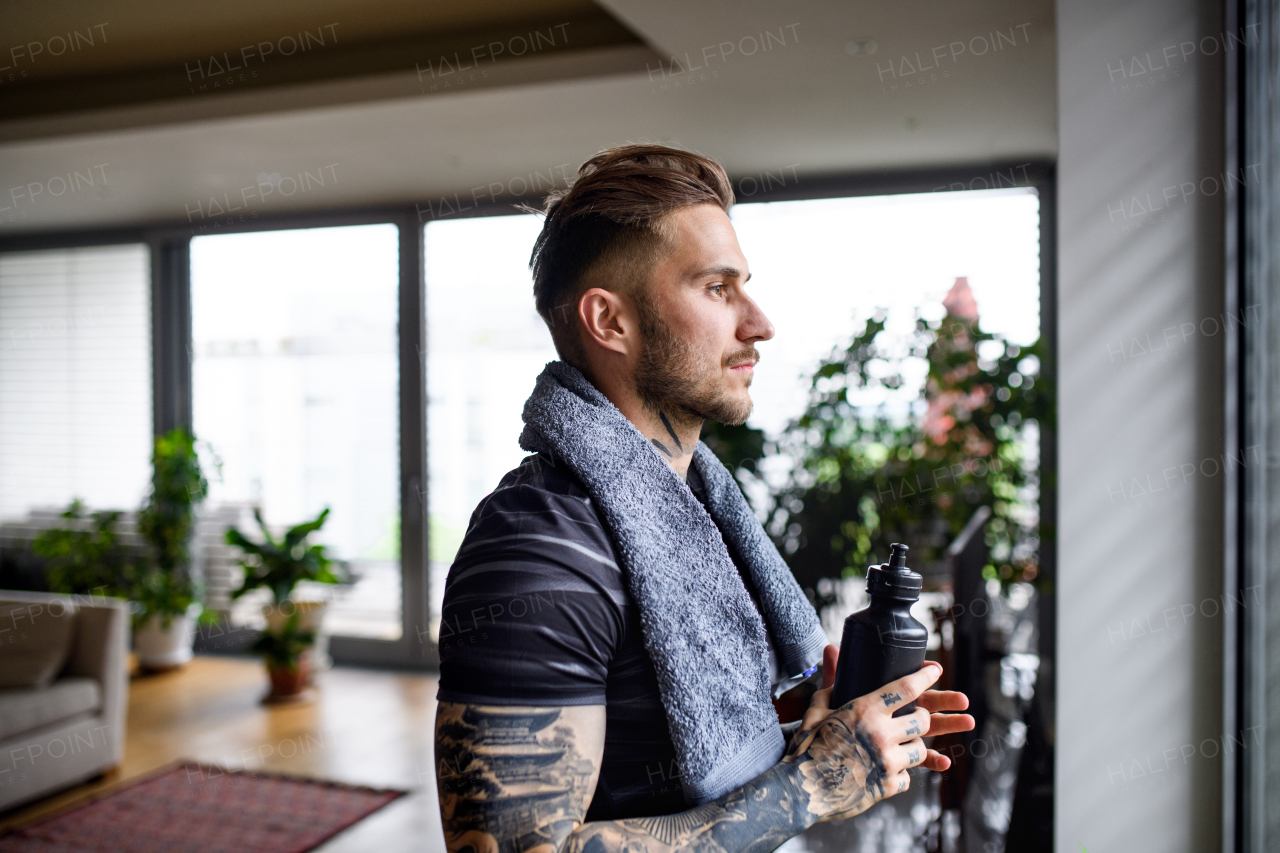 Side view portrait of man resting after workout exercise indoors at home.