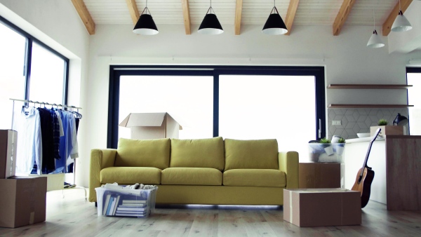 Moving boxes, sofa and clothes rack on the floor in new home. A moving in new home concept.