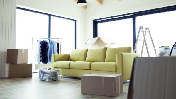 Moving boxes, sofa and clothes rack on the floor in new home. A moving in new home concept.