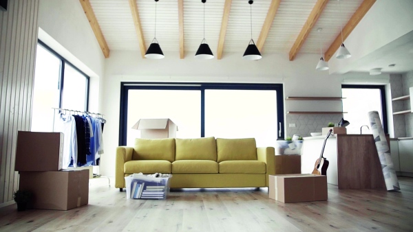 Moving boxes, sofa and clothes rack on the floor in new home. A moving in new home concept. Slow motion.