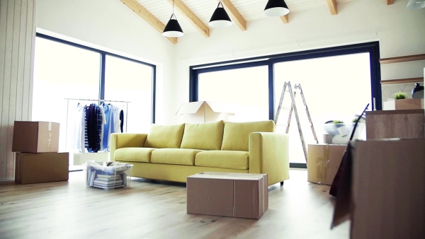 Moving boxes, sofa and clothes rack on the floor in new home. A moving in new home concept. Slow motion.