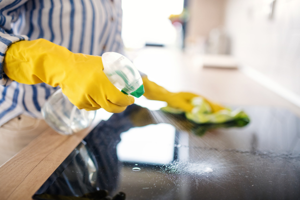 Unrecognizable senior woman cleaning kitchen counter indoors at home, midsection.